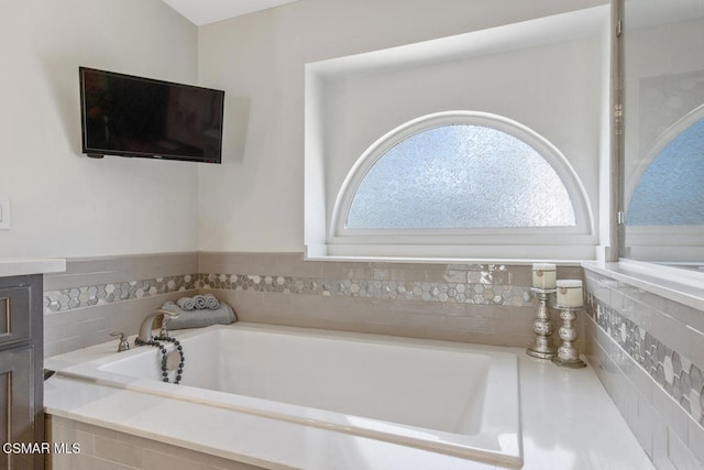 bathroom with vanity and tiled bath