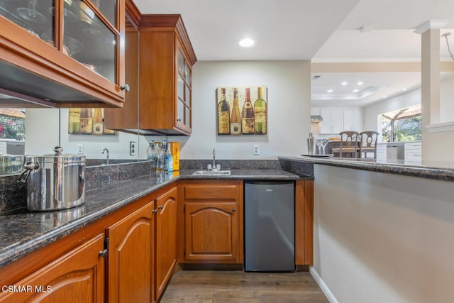 kitchen with dark hardwood / wood-style flooring, sink, stainless steel dishwasher, and dark stone countertops