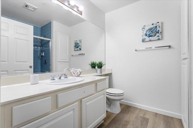 bathroom with vanity, hardwood / wood-style flooring, a shower with door, and toilet