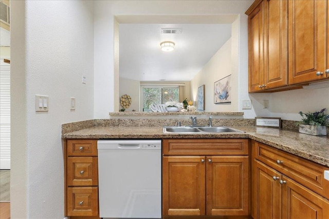 kitchen featuring light stone countertops, sink, white dishwasher, and kitchen peninsula