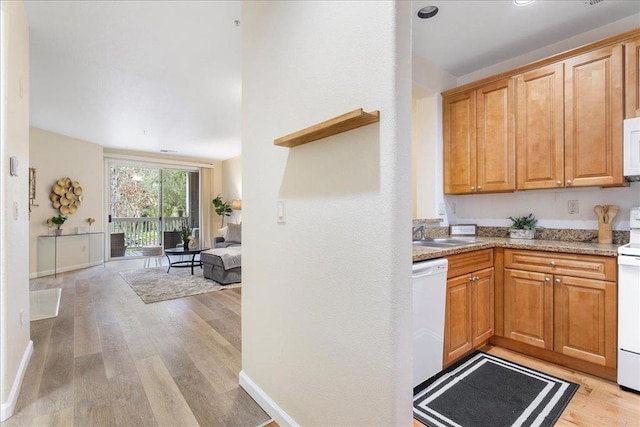 kitchen featuring white appliances, light stone countertops, sink, and light wood-type flooring