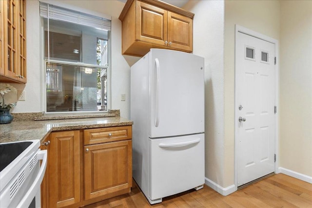 kitchen featuring light stone counters, white appliances, and light hardwood / wood-style flooring