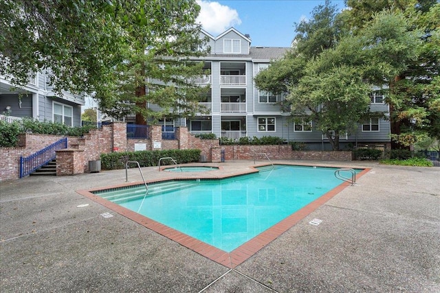 view of pool with cooling unit and a hot tub