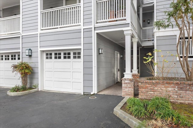 view of exterior entry featuring a balcony and a garage