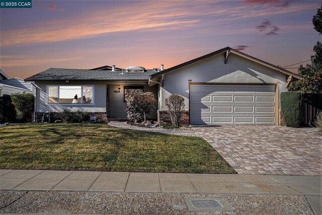 ranch-style home with a garage and a yard