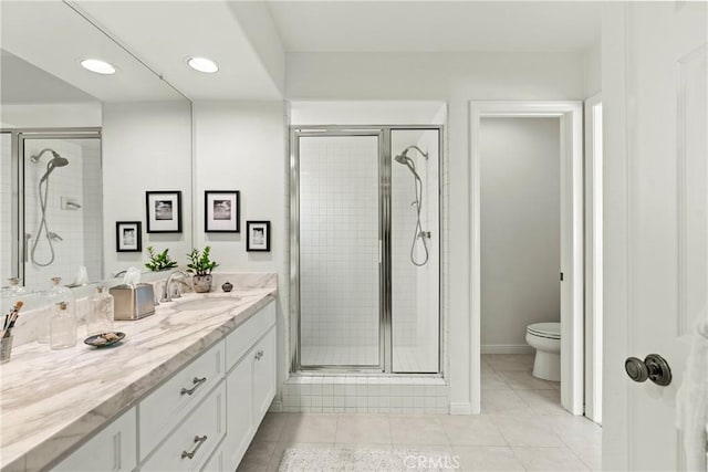 bathroom featuring vanity, a shower with door, tile patterned floors, and toilet