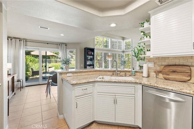 kitchen featuring light tile patterned flooring, white cabinetry, sink, stainless steel dishwasher, and light stone counters