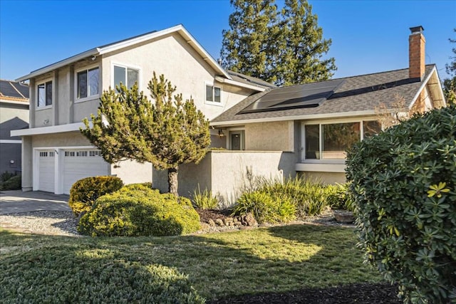 view of front of home with a garage, a front yard, and solar panels