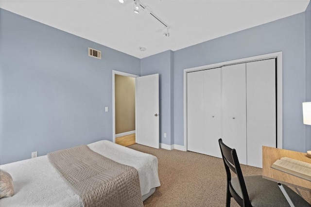 carpeted bedroom with track lighting and a closet