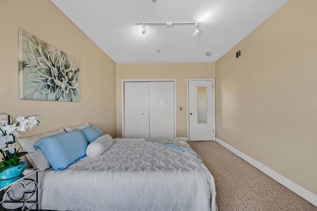 bedroom with track lighting, carpet, and a closet