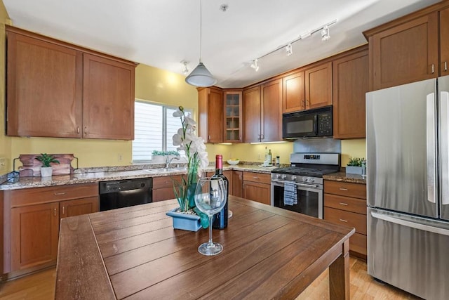 kitchen featuring pendant lighting, dark stone counters, light hardwood / wood-style floors, and black appliances