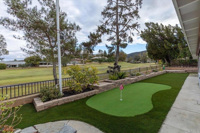 view of community featuring a mountain view, a yard, and fence