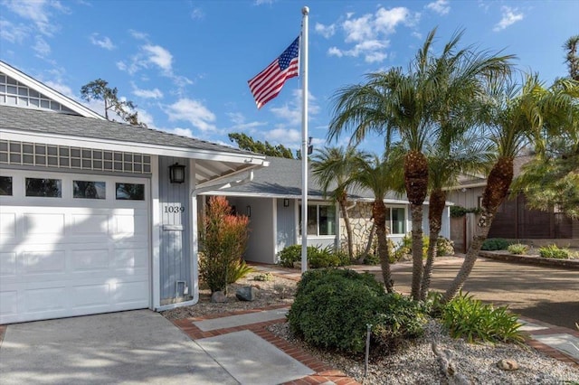 ranch-style house featuring an attached garage and roof with shingles