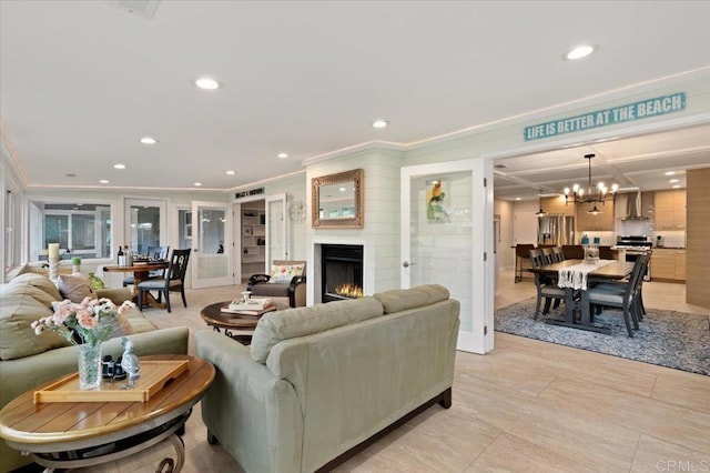 living area with ornamental molding, recessed lighting, a chandelier, and a lit fireplace