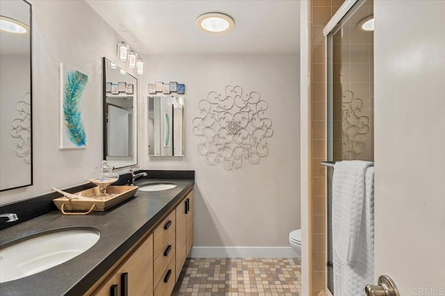 full bathroom with toilet, baseboards, a tile shower, and a sink