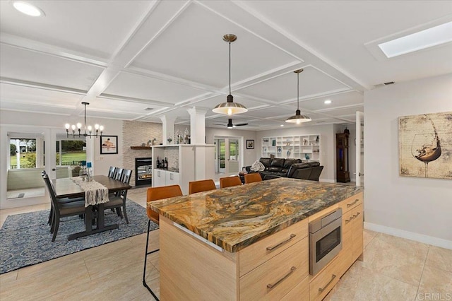 kitchen featuring stainless steel microwave, coffered ceiling, visible vents, and light brown cabinetry