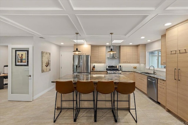 kitchen featuring modern cabinets, a breakfast bar, light brown cabinetry, a kitchen island, and appliances with stainless steel finishes