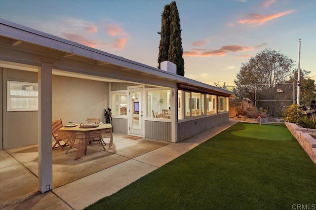 back of house at dusk with a patio area and a chimney