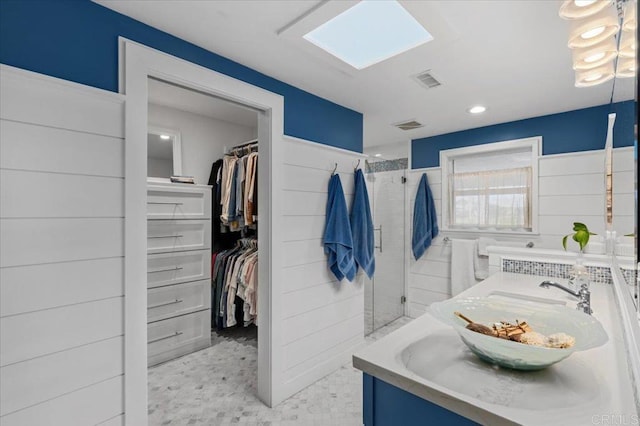 full bathroom with a walk in closet, visible vents, a skylight, and a shower stall