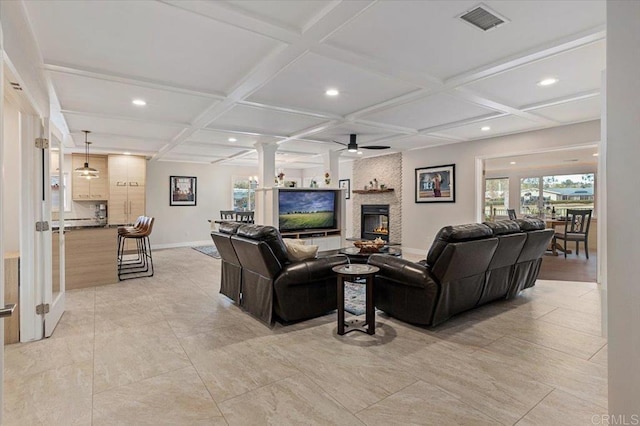 living room with visible vents, a large fireplace, coffered ceiling, and decorative columns