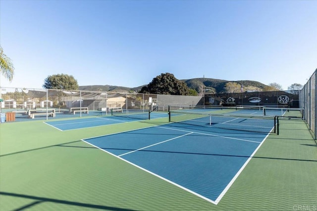 view of sport court with a mountain view and fence