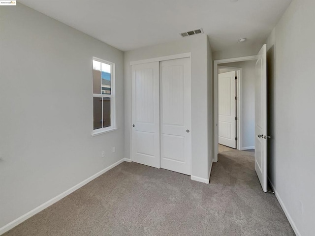 unfurnished bedroom with a closet and light carpet