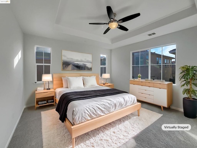 carpeted bedroom featuring ceiling fan and a tray ceiling