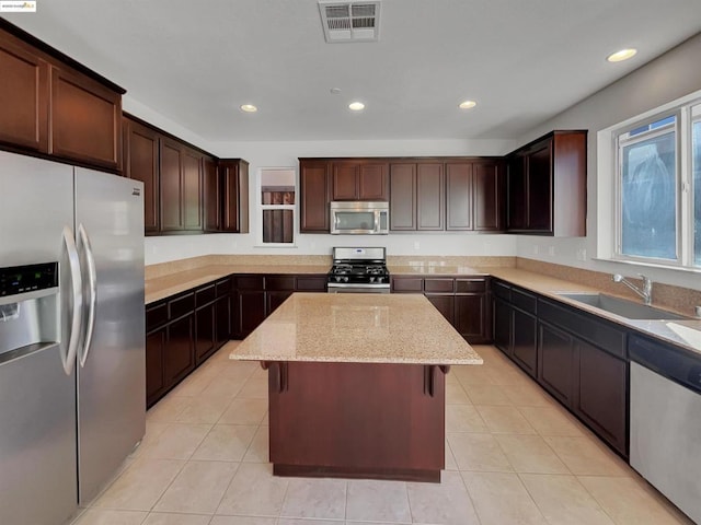 kitchen featuring sink, a kitchen breakfast bar, a kitchen island, stainless steel appliances, and light stone countertops