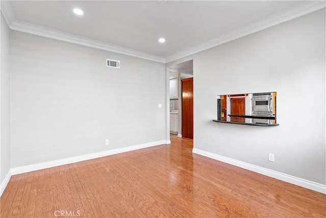 spare room featuring wood finished floors, visible vents, and baseboards