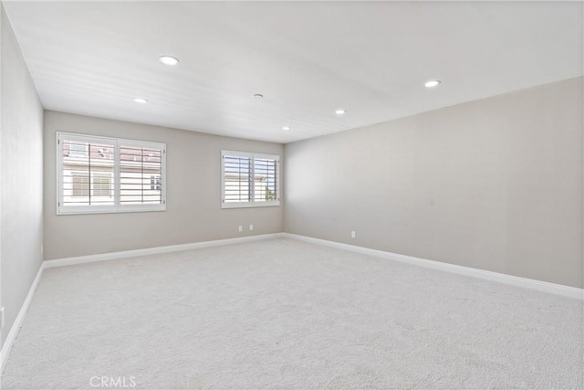 spare room featuring light carpet, recessed lighting, and baseboards