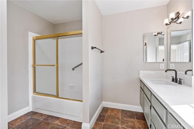 bathroom with bath / shower combo with glass door, stone finish floor, vanity, and baseboards