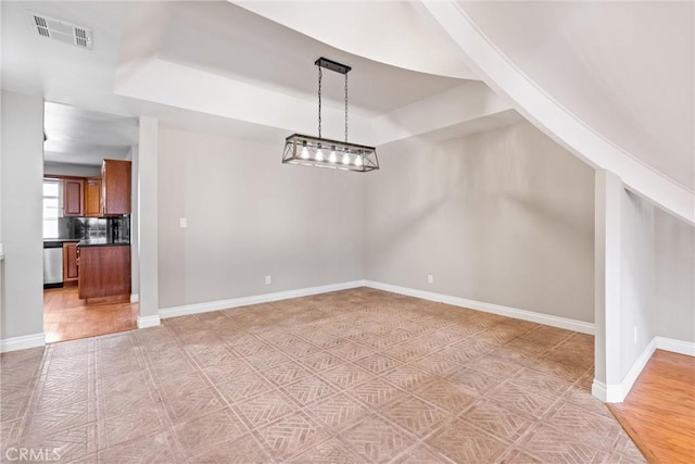 unfurnished dining area featuring baseboards, visible vents, and a raised ceiling