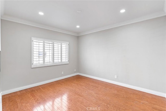 spare room with light wood-style floors, recessed lighting, ornamental molding, and baseboards