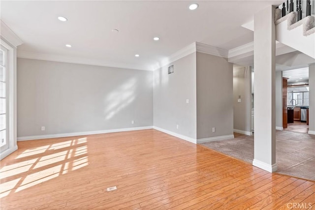 empty room with light wood-type flooring, baseboards, ornamental molding, and recessed lighting