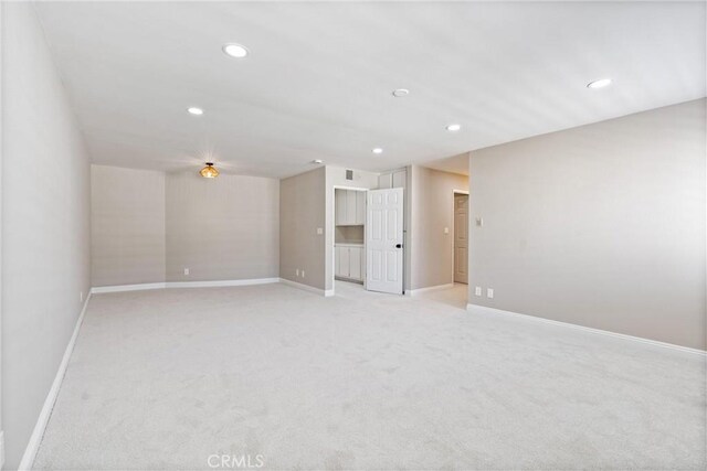 empty room featuring baseboards, light carpet, and recessed lighting