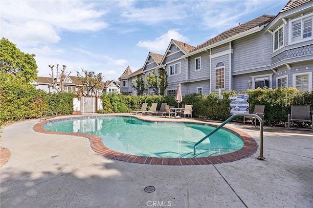 view of swimming pool featuring a patio, fence, a residential view, and a fenced in pool