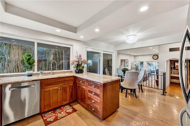 kitchen with stainless steel appliances, light stone countertops, sink, and light wood-type flooring