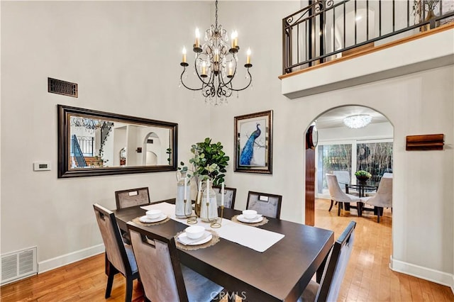 dining space featuring hardwood / wood-style flooring, a high ceiling, and a notable chandelier