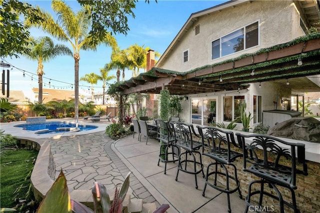 view of patio / terrace featuring a pergola, an outdoor bar, pool water feature, and a jacuzzi