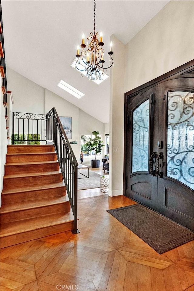 foyer with french doors, parquet flooring, lofted ceiling, and an inviting chandelier