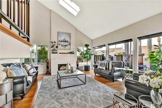 living room with plenty of natural light, a skylight, high vaulted ceiling, and wood-type flooring