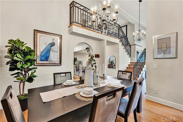 dining area featuring beamed ceiling, light wood-type flooring, an inviting chandelier, and a towering ceiling