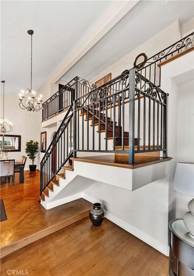 stairway with an inviting chandelier and hardwood / wood-style floors