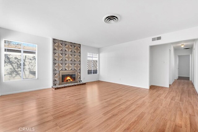 unfurnished living room with a wealth of natural light, a fireplace, and light wood-type flooring