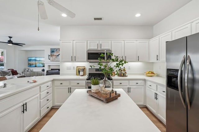 kitchen featuring appliances with stainless steel finishes, white cabinetry, sink, ceiling fan, and light wood-type flooring