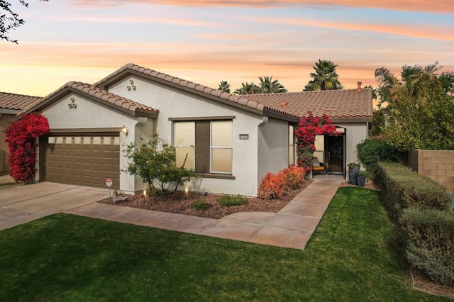 mediterranean / spanish-style house with a garage and a yard