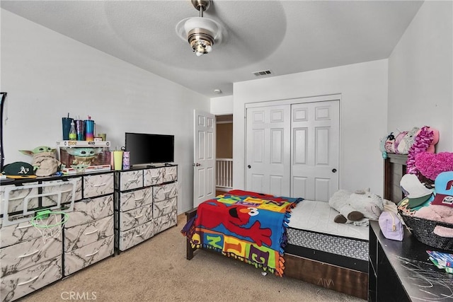 carpeted bedroom featuring ceiling fan and a closet