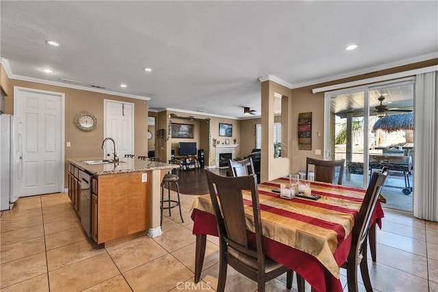 tiled dining room with ceiling fan, ornamental molding, and sink