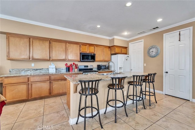 kitchen with white refrigerator with ice dispenser, a kitchen island with sink, stainless steel stove, and light stone counters