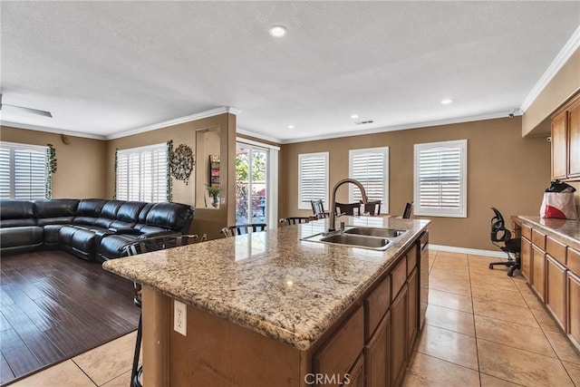 kitchen with a kitchen island with sink, sink, light tile patterned floors, and ornamental molding